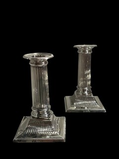 An English Pair of Edwardian Sterling Silver Candlesticks designed as fluted Classical columns on stepped square bases.